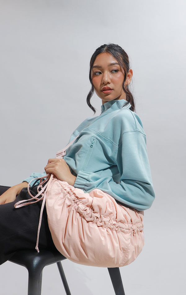 Campaign photo of the Pink Dumpling Shoulder Bag with Drawstring Details worn by a model with outfit 
