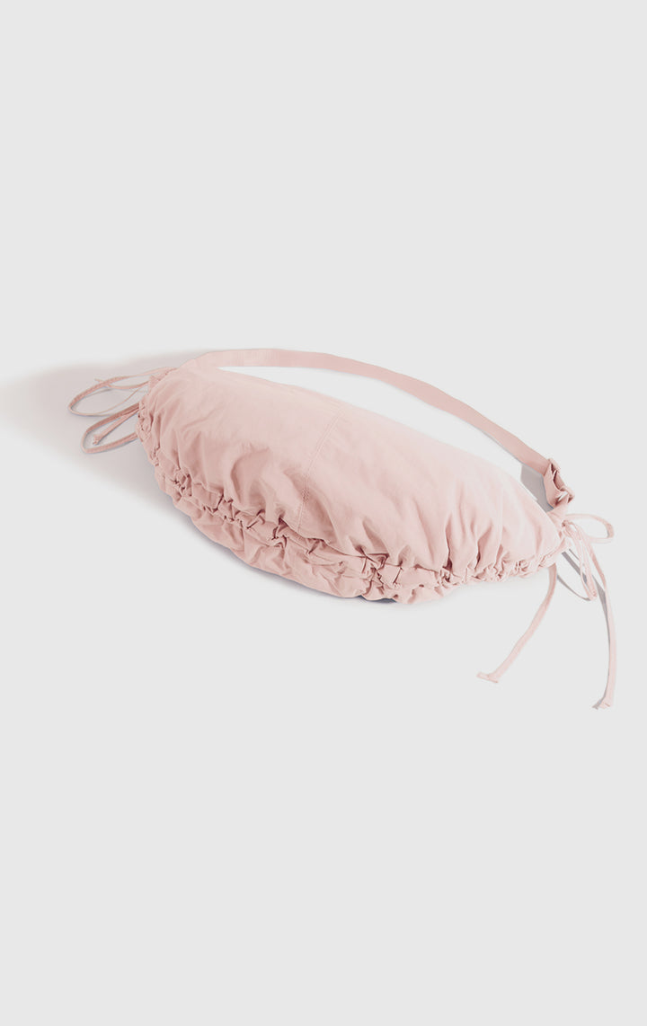 Stylized photo of the Pink Dumpling Shoulder Bag with Drawstring on minimal setup