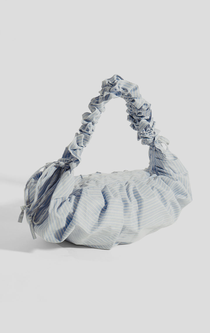 Stylized photo of the Blue Nylon Stripes Dumpling Shoulder Bag with Ruched Handle on minimal setup