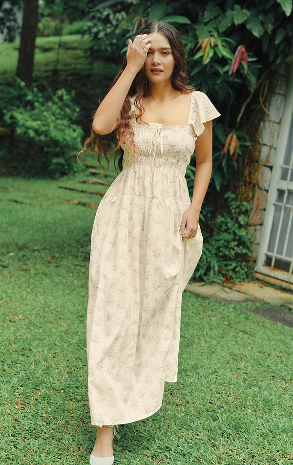 Campaign photo of the floral smocked maxi dress with flutter sleeves, square neckline, and maxi length that shows how it looks when worn, from the Just G Love In Bloom collection