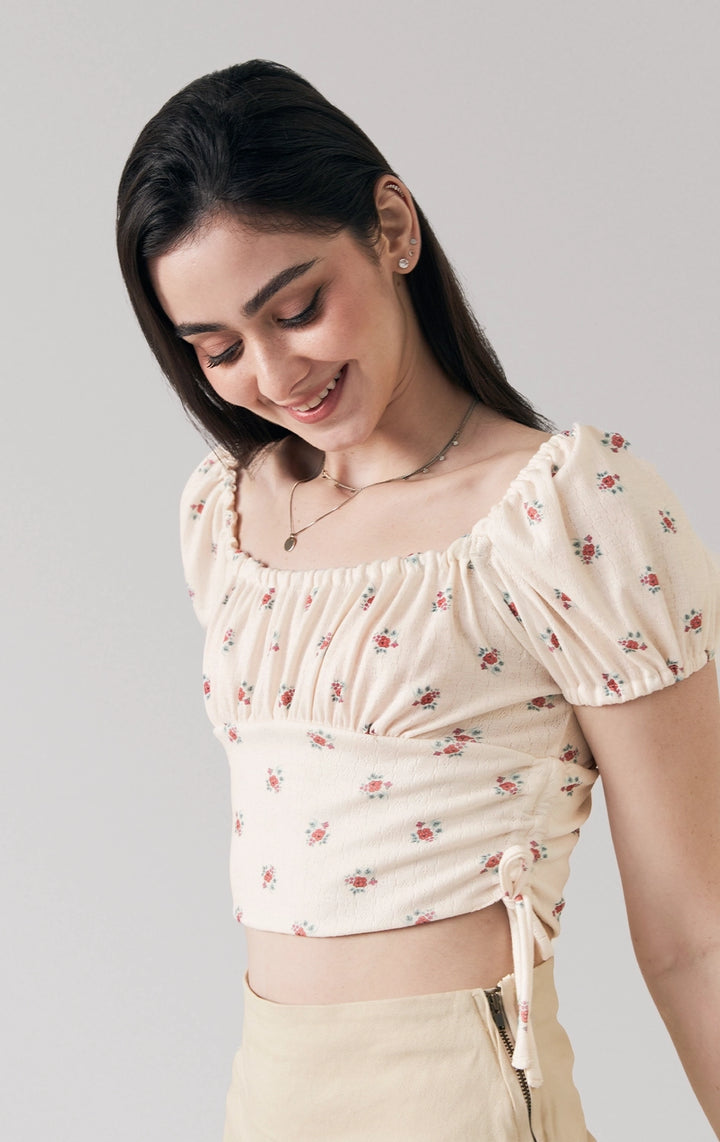 A stylized fashion photo of the floral print puff sleeve crop top with side ties that is worn with bottoms and accessories by a model to see it in motion