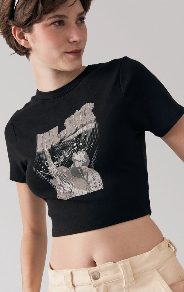 A stylized fashion photo of the baby tee with "Love to Rock" graphics that is worn with bottoms and accessories by a model to see it in motion