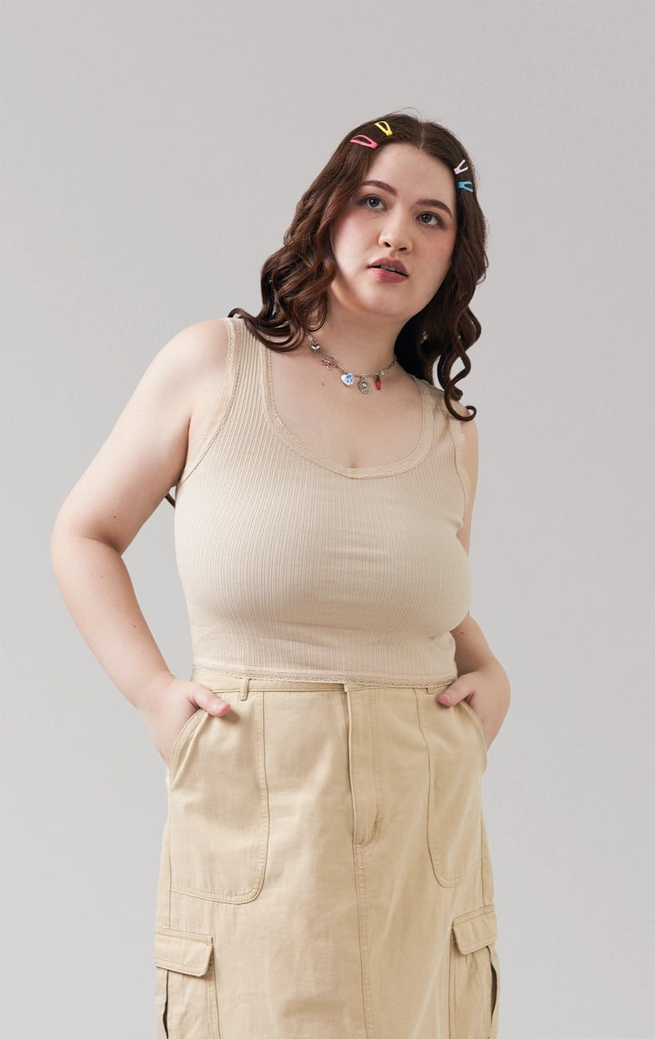 A stylized fashion photo of the off-white ribbed tank top with lace and bow with bottoms and accessories that is worn by a model to see it in motion 