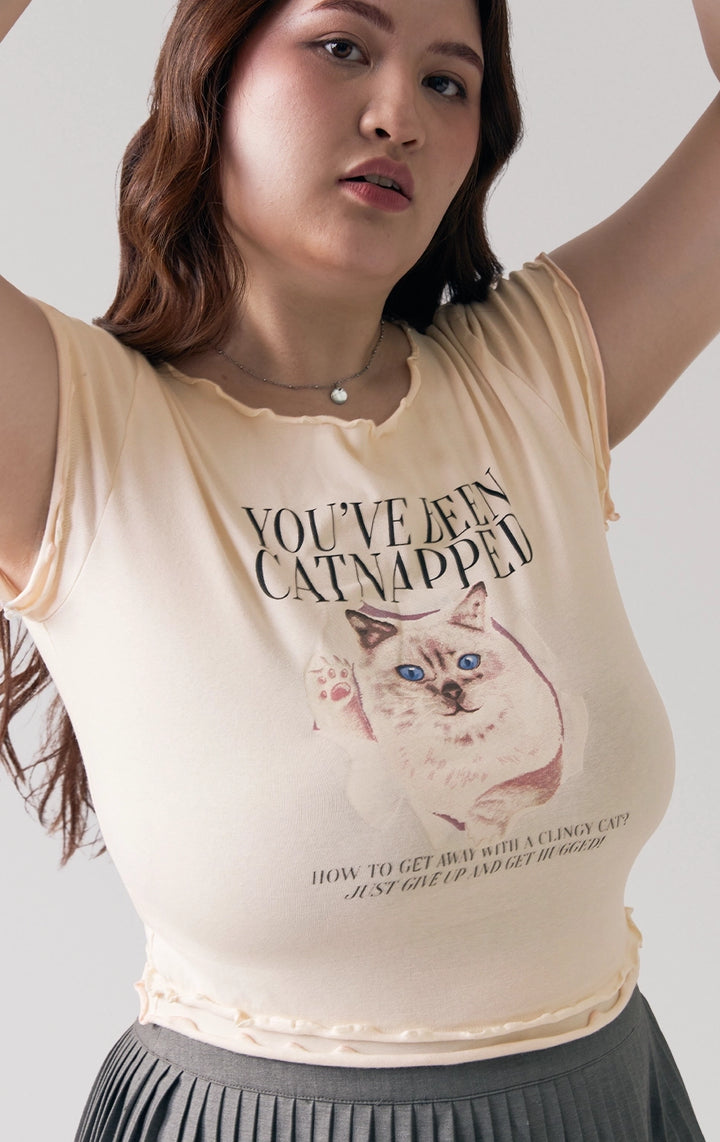 A stylized fashion photo of lettuce edge tee with cat graphic that is worn with bottoms and accessories by a model to see it in motion