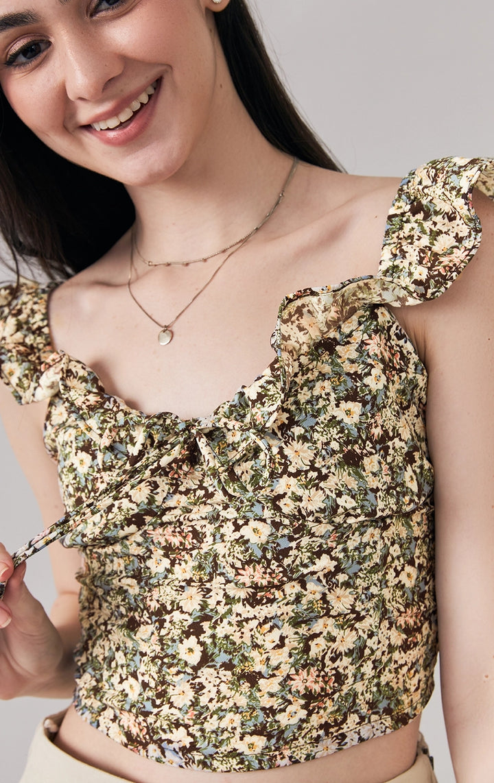 A stylized fashion photo of the floral bustier top with tie that is worn with bottoms and accessories by a model to see it in motion