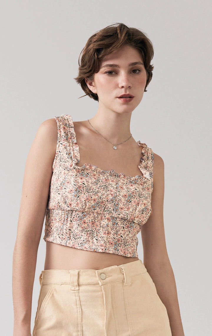 A stylized fashion photo of the floral ruffled crop top that is worn with bottoms and accessories by a model to see it in motion