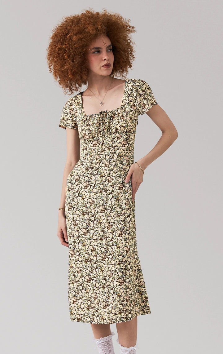 A stylized fashion photo of the floral midi dress with tie detail that is worn by a model to see it in motion.
