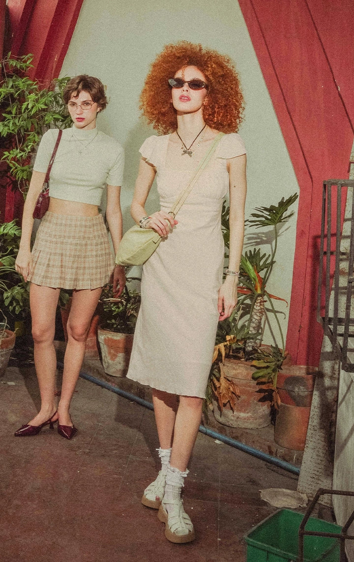 Campaign photo of model wearing the Flutter Sleeve Symmetrical Hem Midi Dress With Lace And Rosebud in offwhite, from the back to school collection of Gen Z women's brand Just G Philippines.