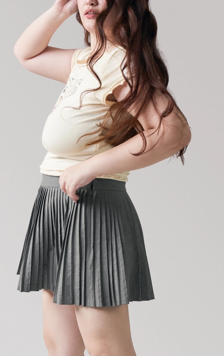 A stylized fashion photo of the pleated mini skirt that is worn with a top and accessories by a model to see it in motion